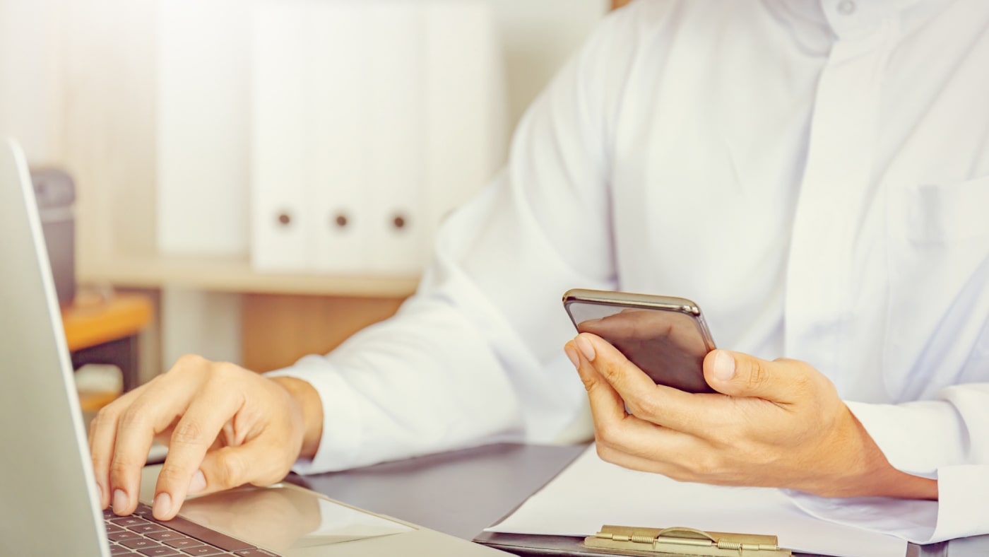 Image of a business professional in Kuwait using digital tools like a laptop and smartphone.
